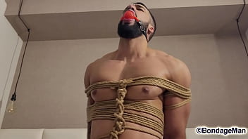 Leo Oliver muscular naked guy is tied up in the bed, ballgagged, bandana gag helpless struggling | PREVIEW