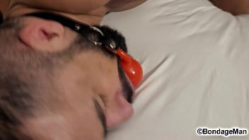 Leo Oliver muscular naked guy is tied up in the bed, ballgagged, bandana gag helpless struggling | PREVIEW
