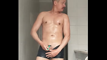 Sexy guy in black beach shorts shaving